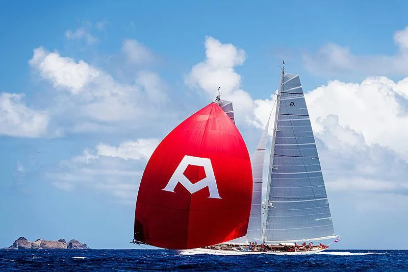 a red and white flag and a red and white striped flag on a beach with a blue sky aboard ADELA Yacht for Sale