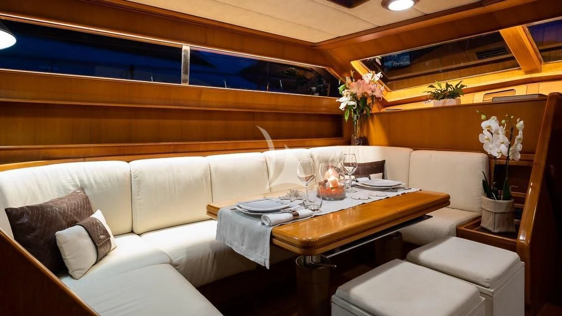 a room with a couch and a table with wine glasses aboard LOTTY Yacht for Sale