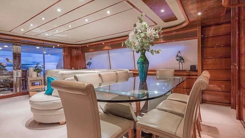 a room with a table chairs and a vase with flowers in it aboard NOAH'S Yacht for Sale