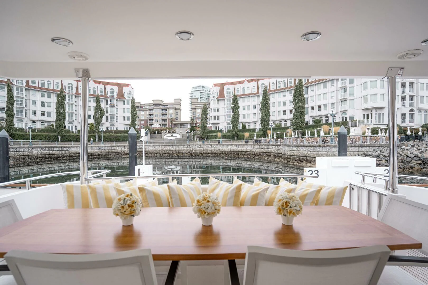 a table with flowers in front of a window with a city in the background aboard HAPPINESS II Yacht for Sale