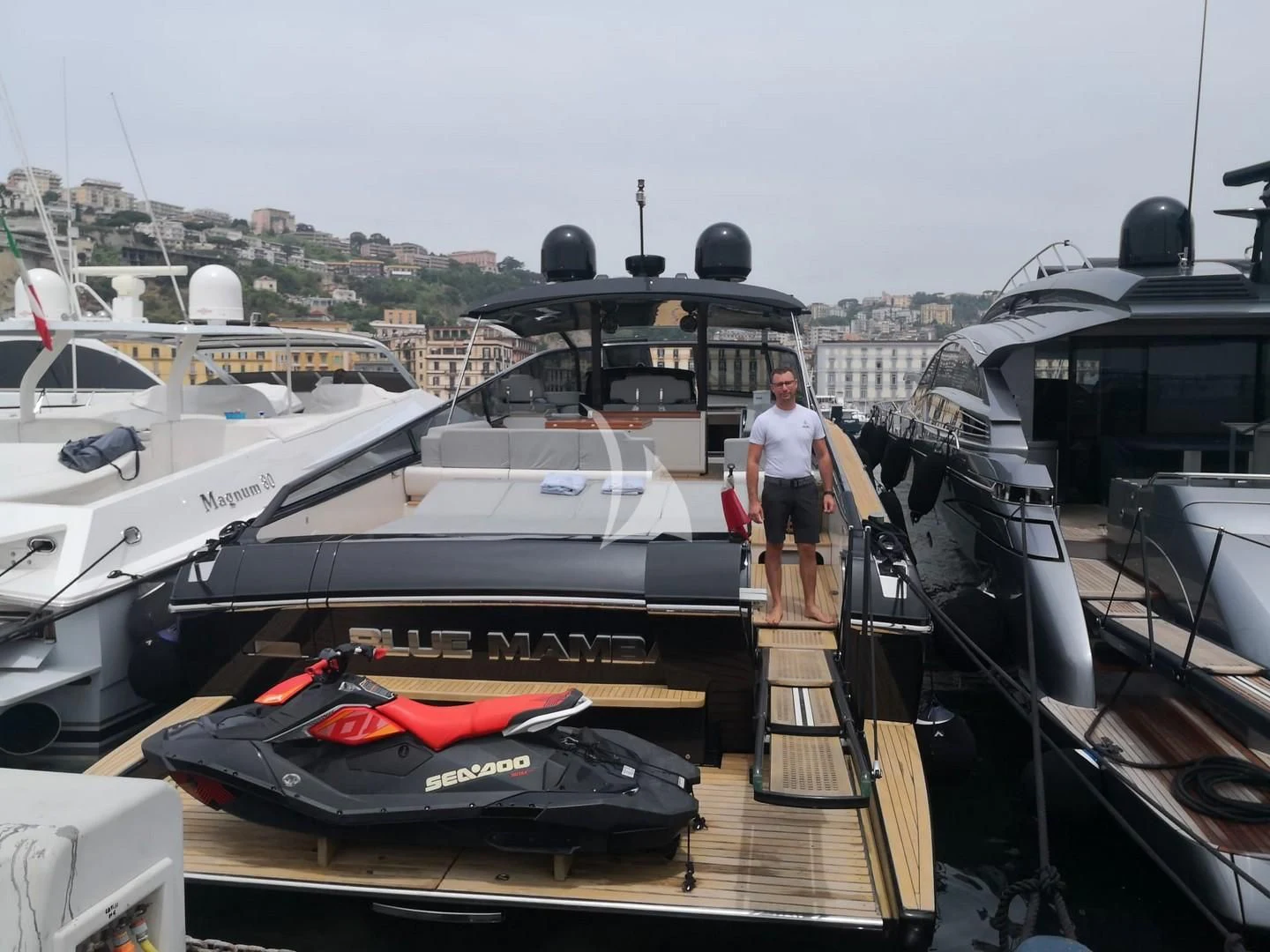 a person standing on a deck next to a boat aboard BLUE MAMBA Yacht for Sale