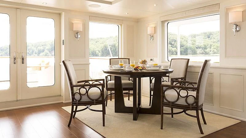 a dining table and chairs in a room with a large window aboard ENDEAVOUR 2 Yacht for Sale