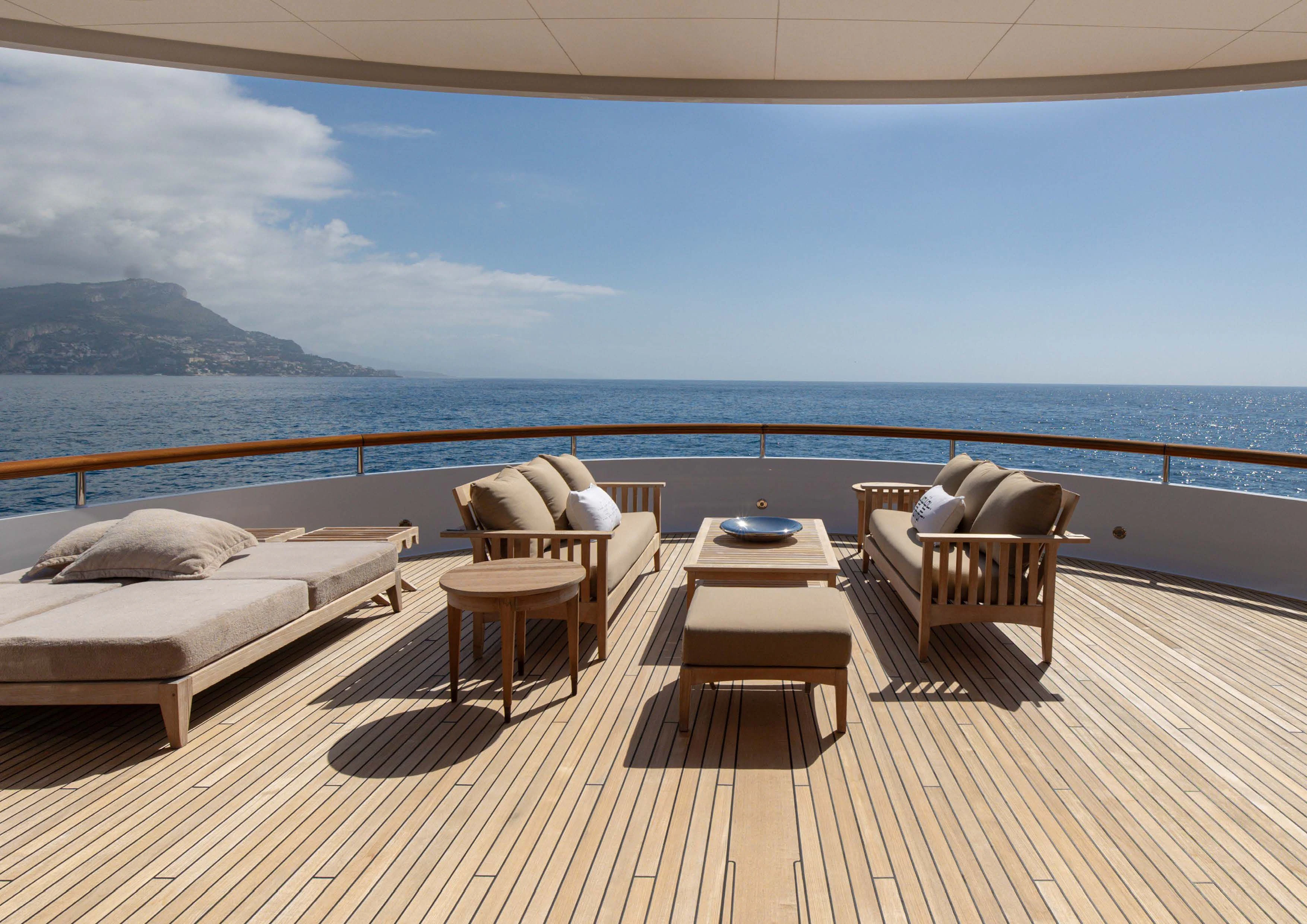a room with a couch and a table and chairs on a deck aboard WEDGE TOO Yacht for Sale