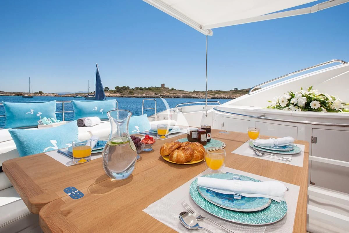 a table with a plate of food and a glass of juice on it aboard FROGGY Yacht for Sale