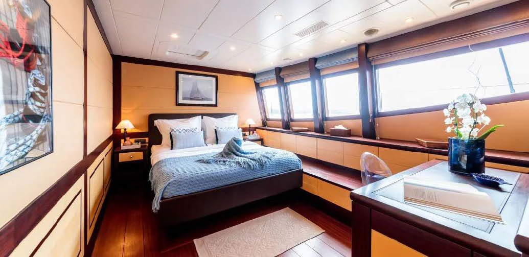 a room with a bed and a desk aboard ALLURES Yacht for Charter