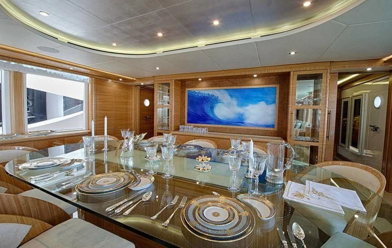 a large dining table with plates and glasses on it aboard UAQ 1 Yacht for Sale