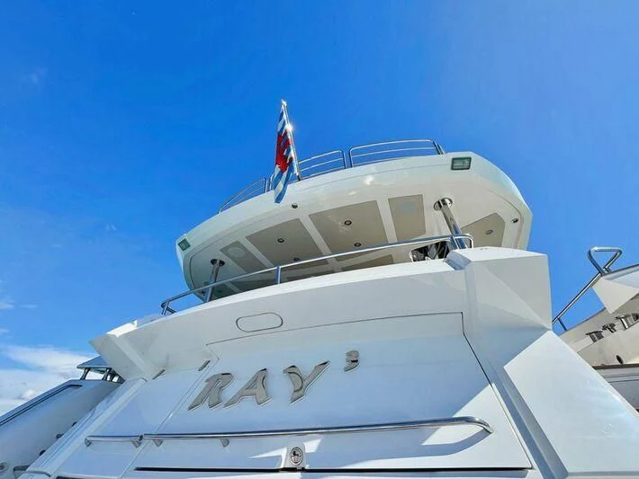 a white yacht with a flag on the front aboard RAY 3 Yacht for Sale