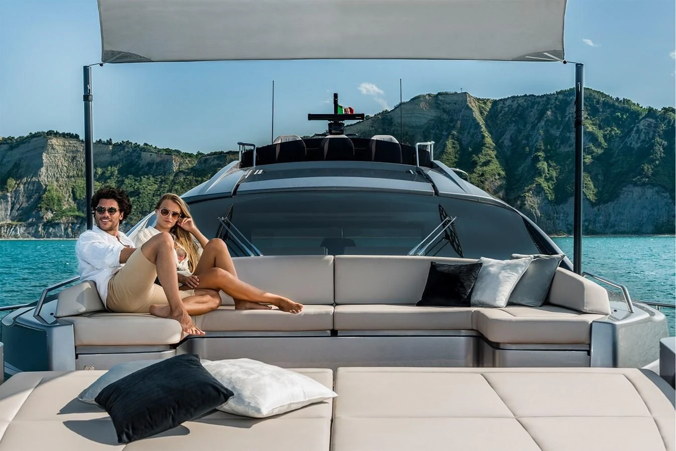 a man and woman sitting on a couch in front of a large pool aboard PERSHING 8X Yacht for Sale