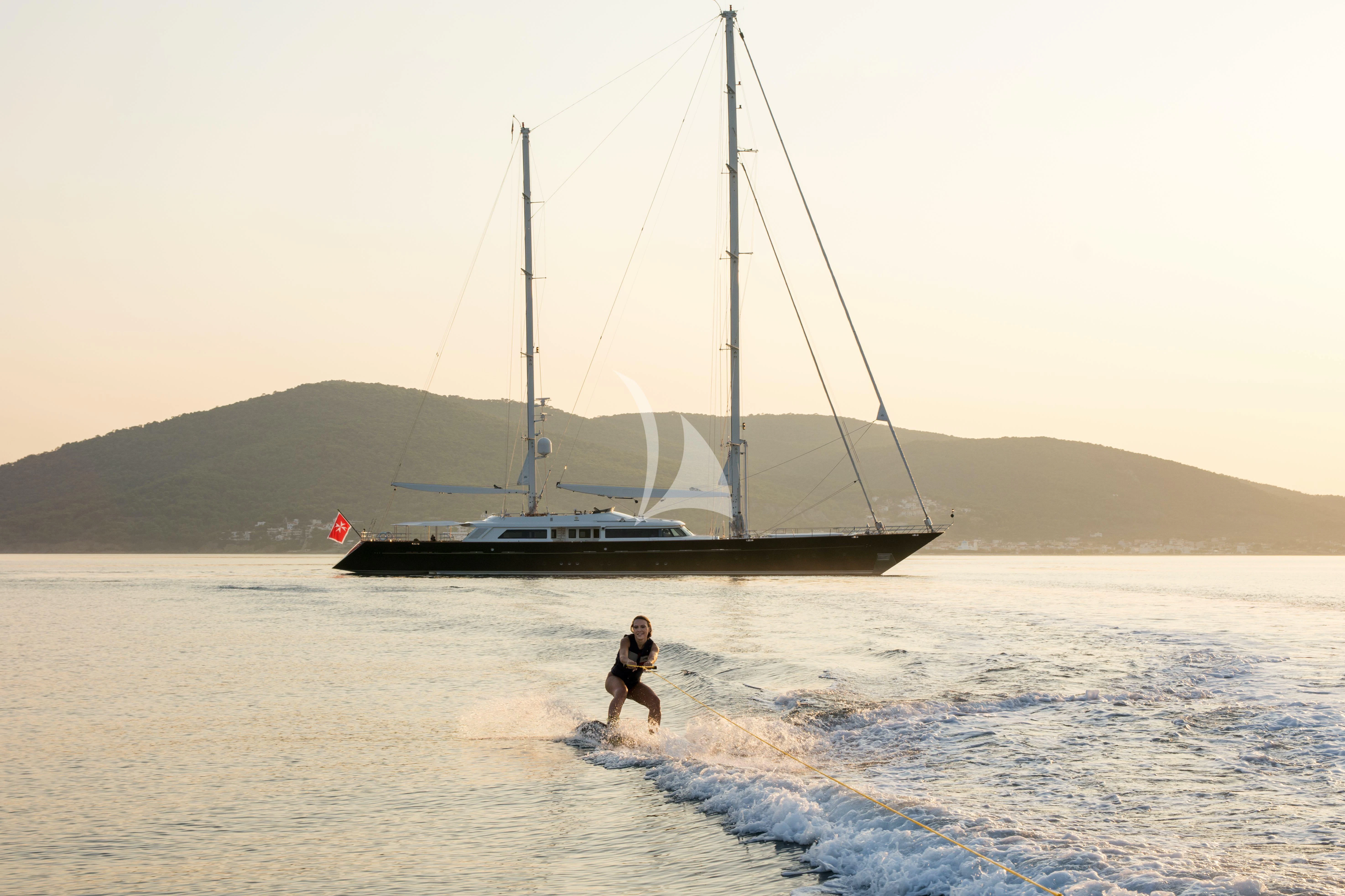 a person walking in water next to a sailboat aboard XASTERIA Yacht for Charter