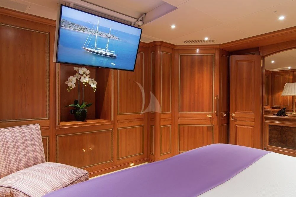 a room with a bed and a television aboard XASTERIA Yacht for Charter