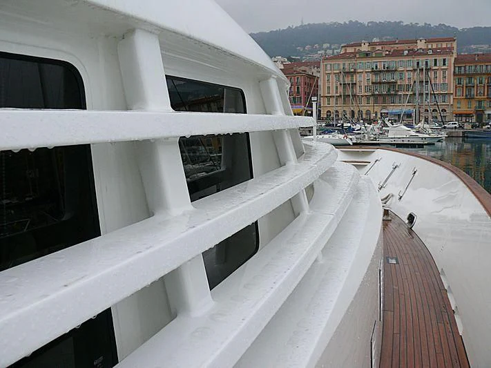a deck with a railing and a city in the background aboard AN Yacht for Sale