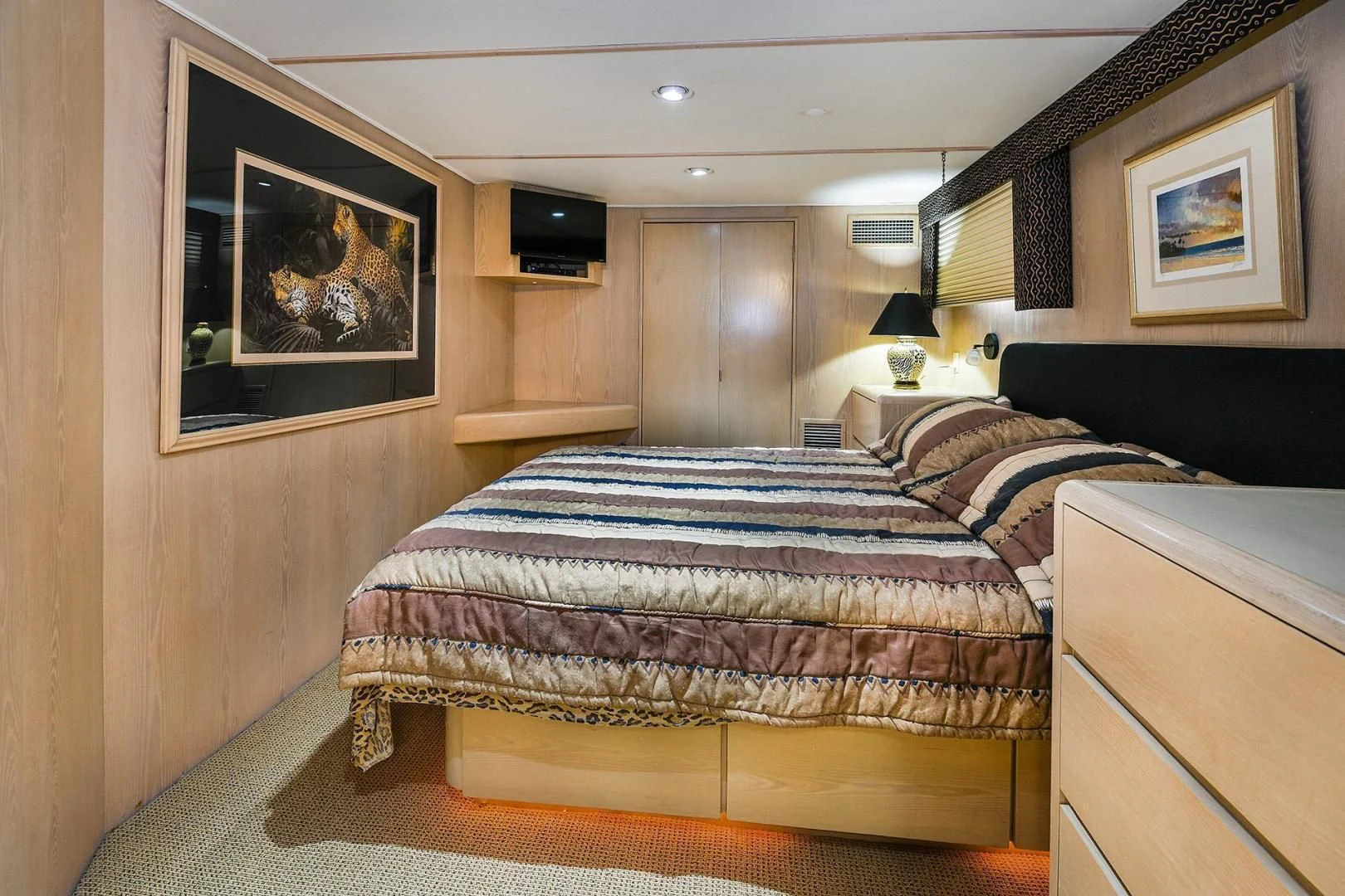 a bedroom with a bed and a painting on the wall aboard PRIMETIME III Yacht for Sale
