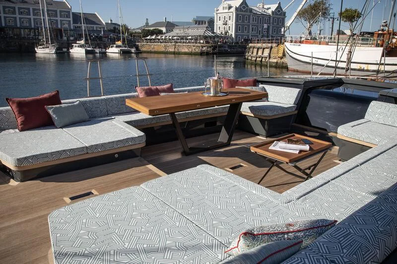 a table and chairs on a deck overlooking a body of water aboard NYUMBA GT Yacht for Sale