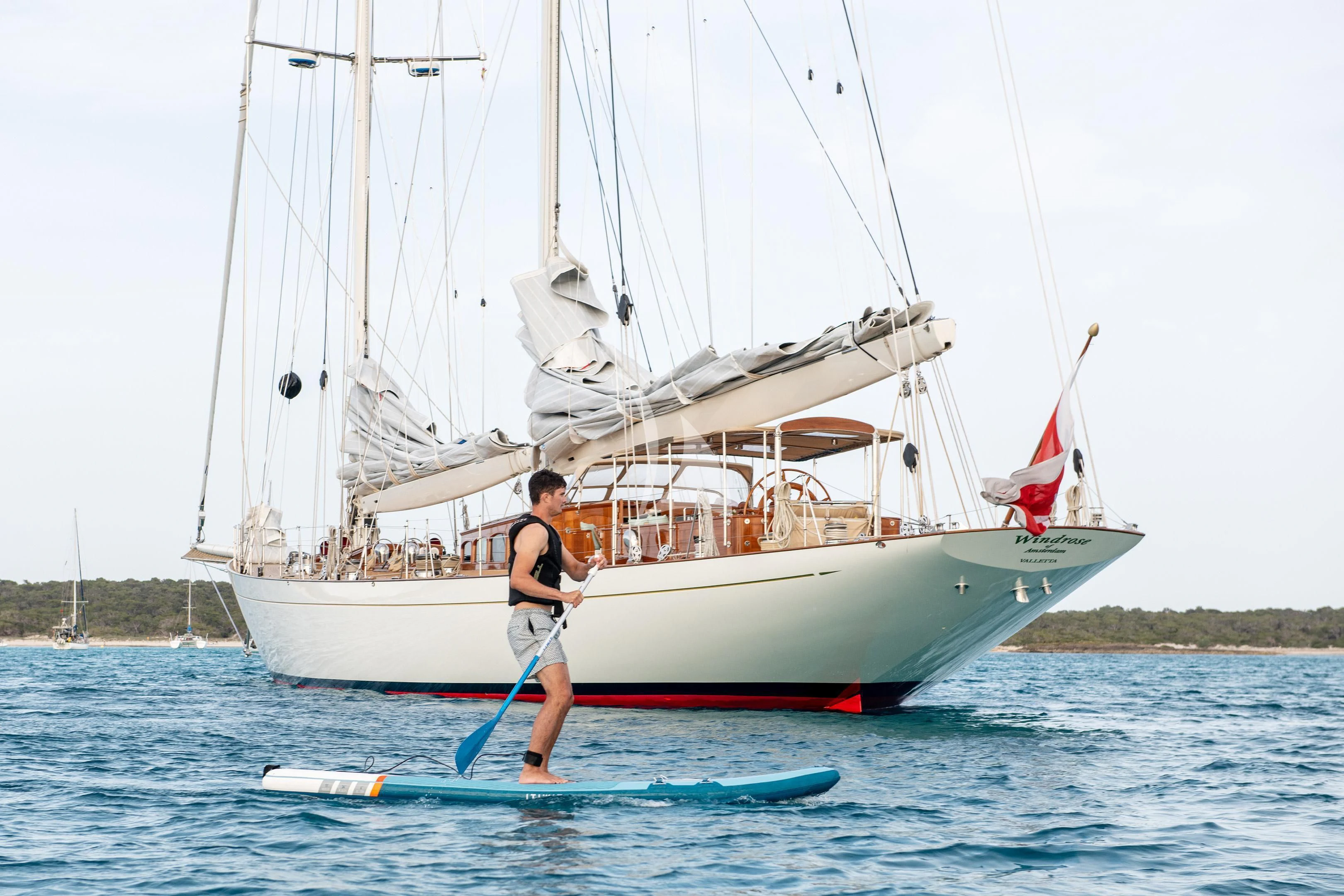 a person on a surfboard next to a sailboat aboard WINDROSE OF AMSTERDAM Yacht for Sale