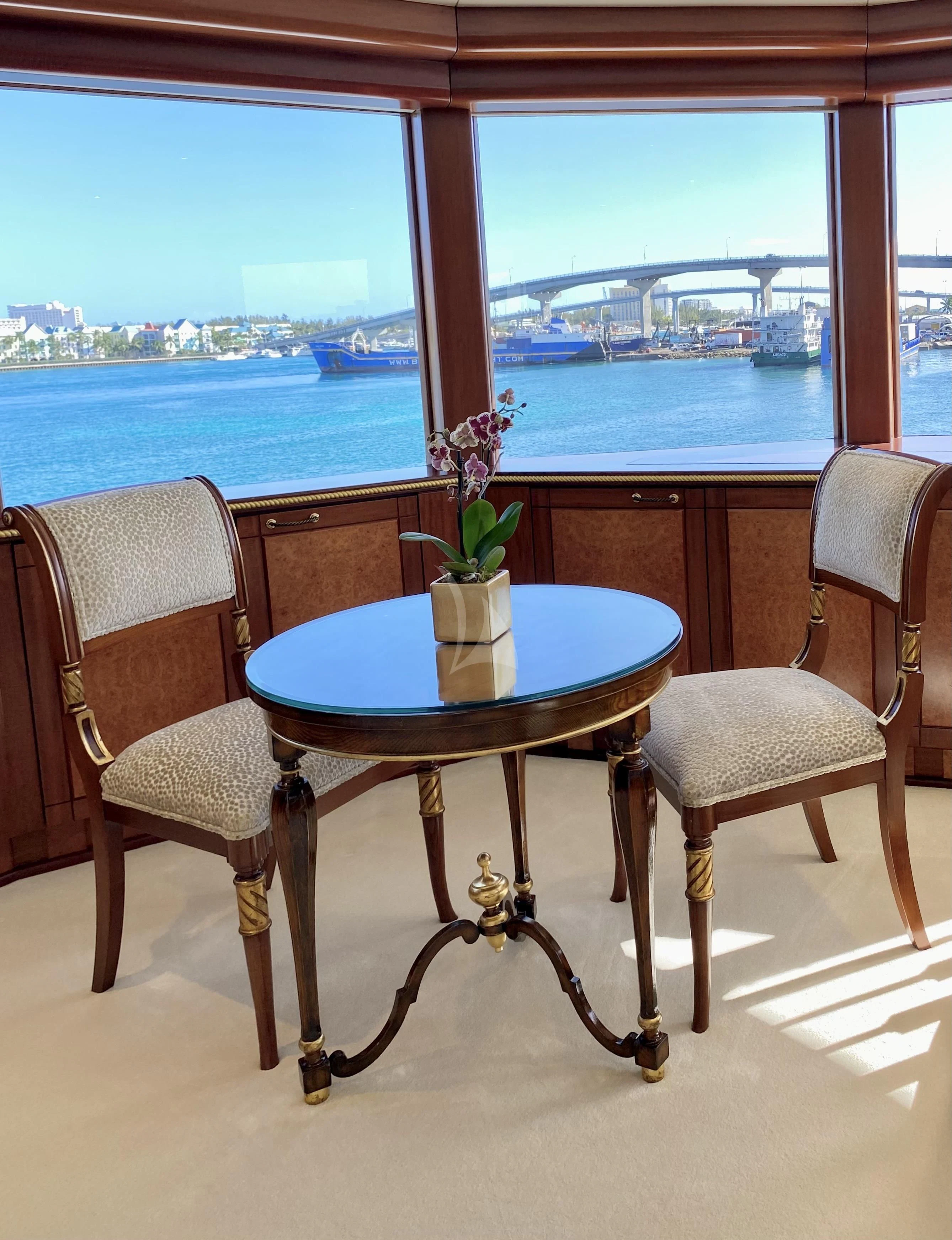 a table with chairs and a plant on it by a window aboard STARSHIP Yacht for Charter