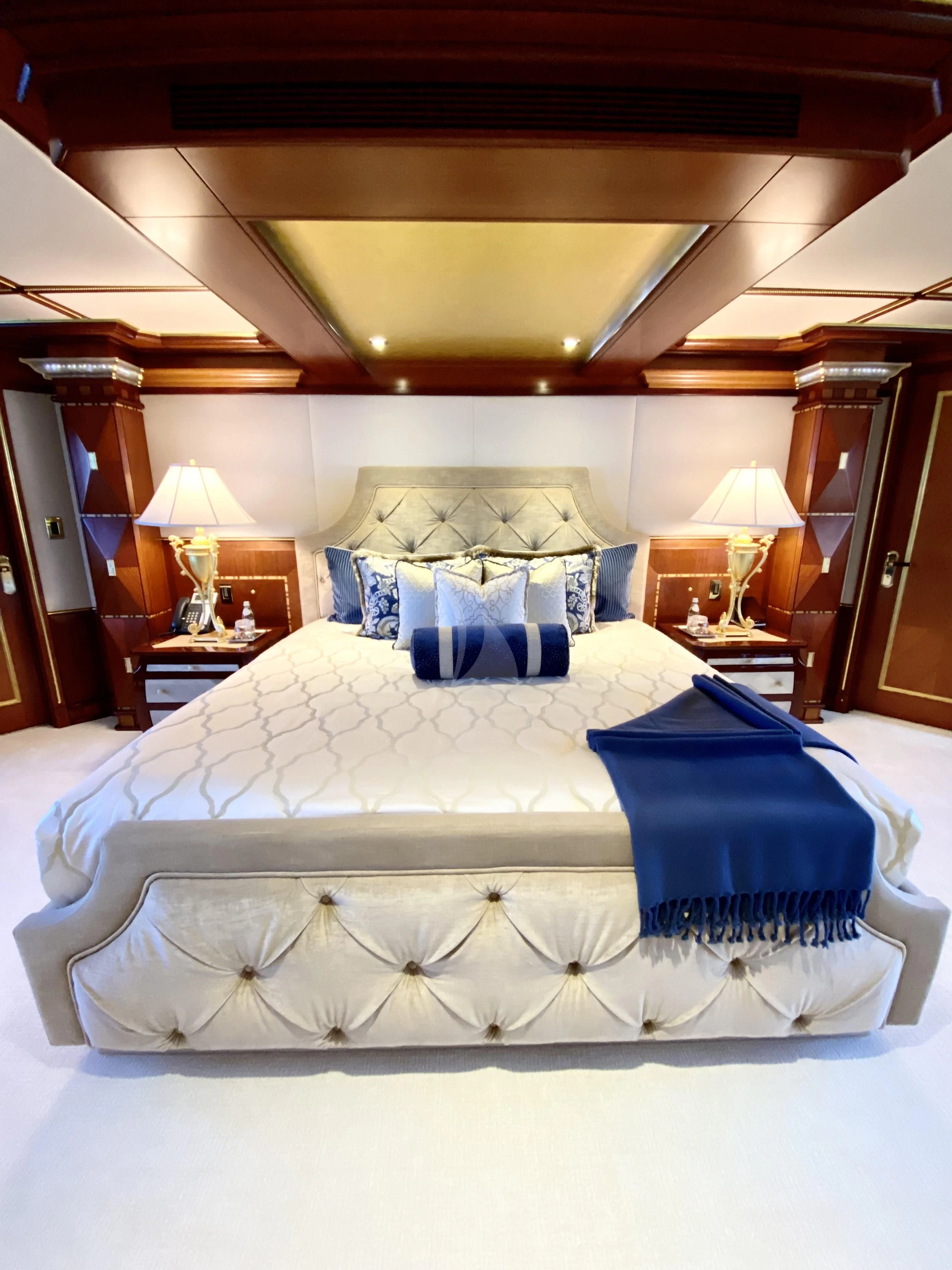 a bed with blue and white sheets aboard STARSHIP Yacht for Charter