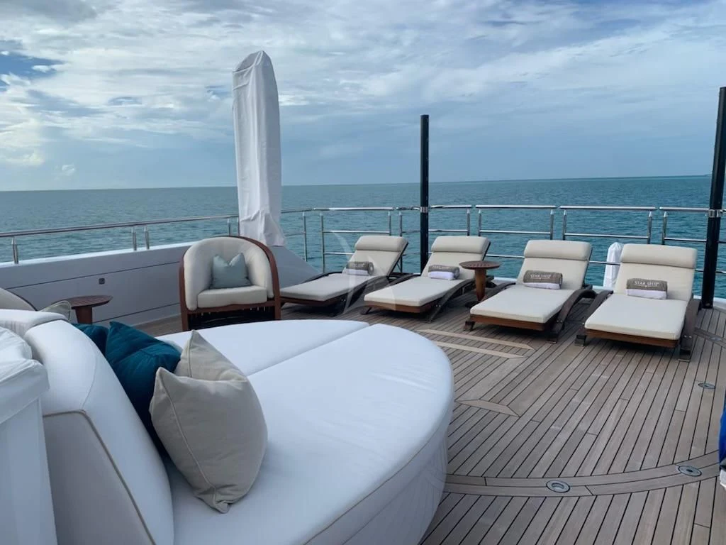 a deck with chairs and a table on it aboard STARSHIP Yacht for Charter