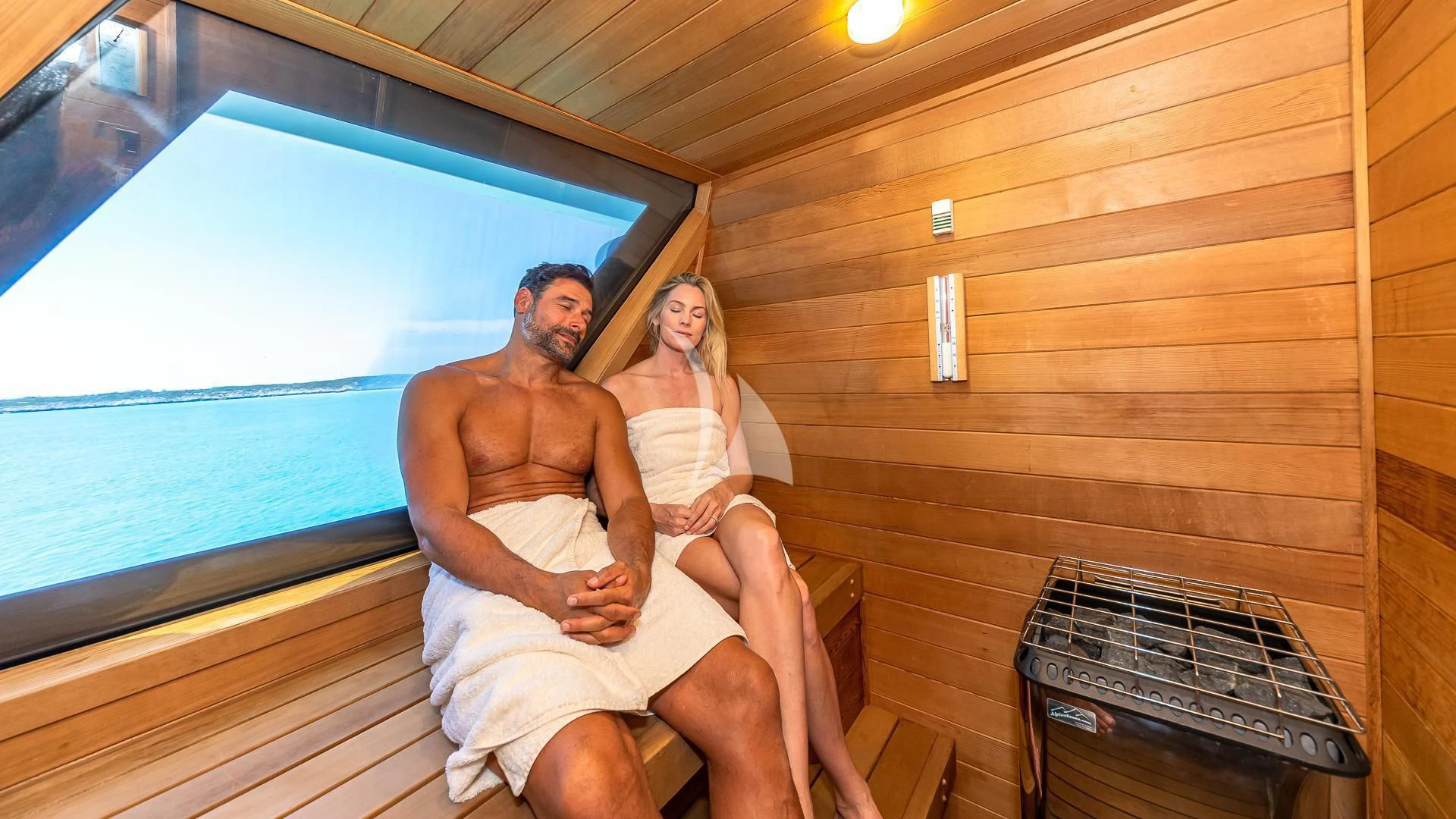a man and woman sitting on a bench in a cabin aboard STARSHIP Yacht for Charter
