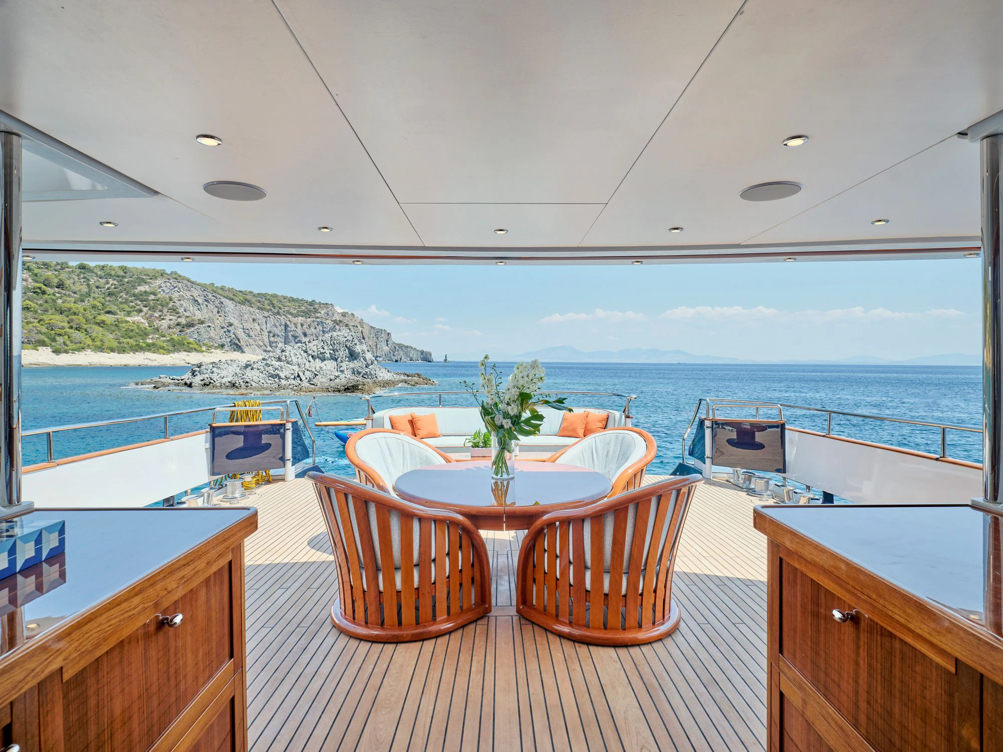 a table and chairs on a deck overlooking a body of water aboard MIA ZOI Yacht for Charter