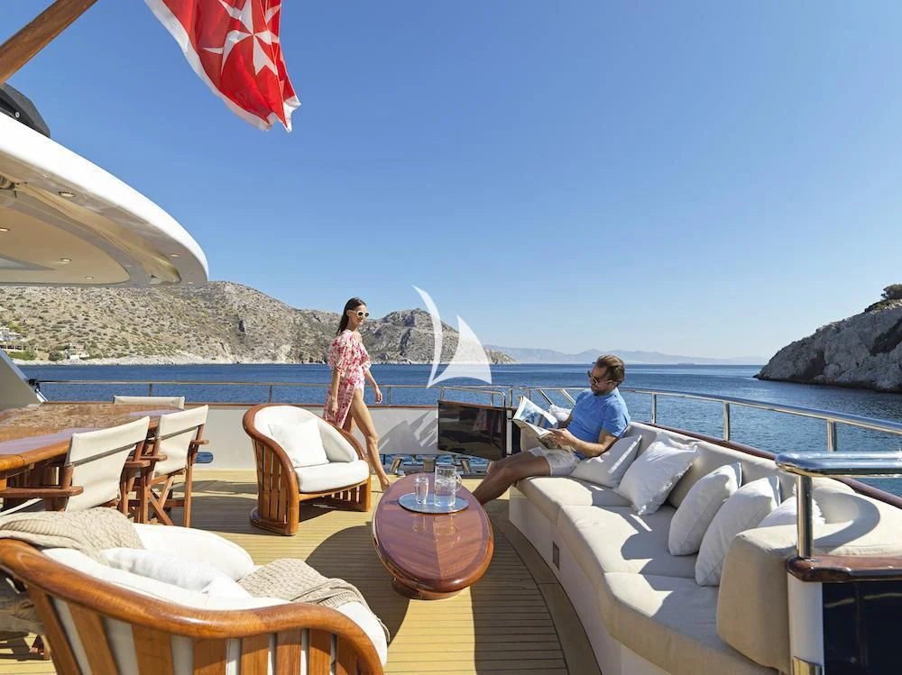 people sitting on lounge chairs on a beach with a body of water in the background aboard MIA ZOI Yacht for Charter