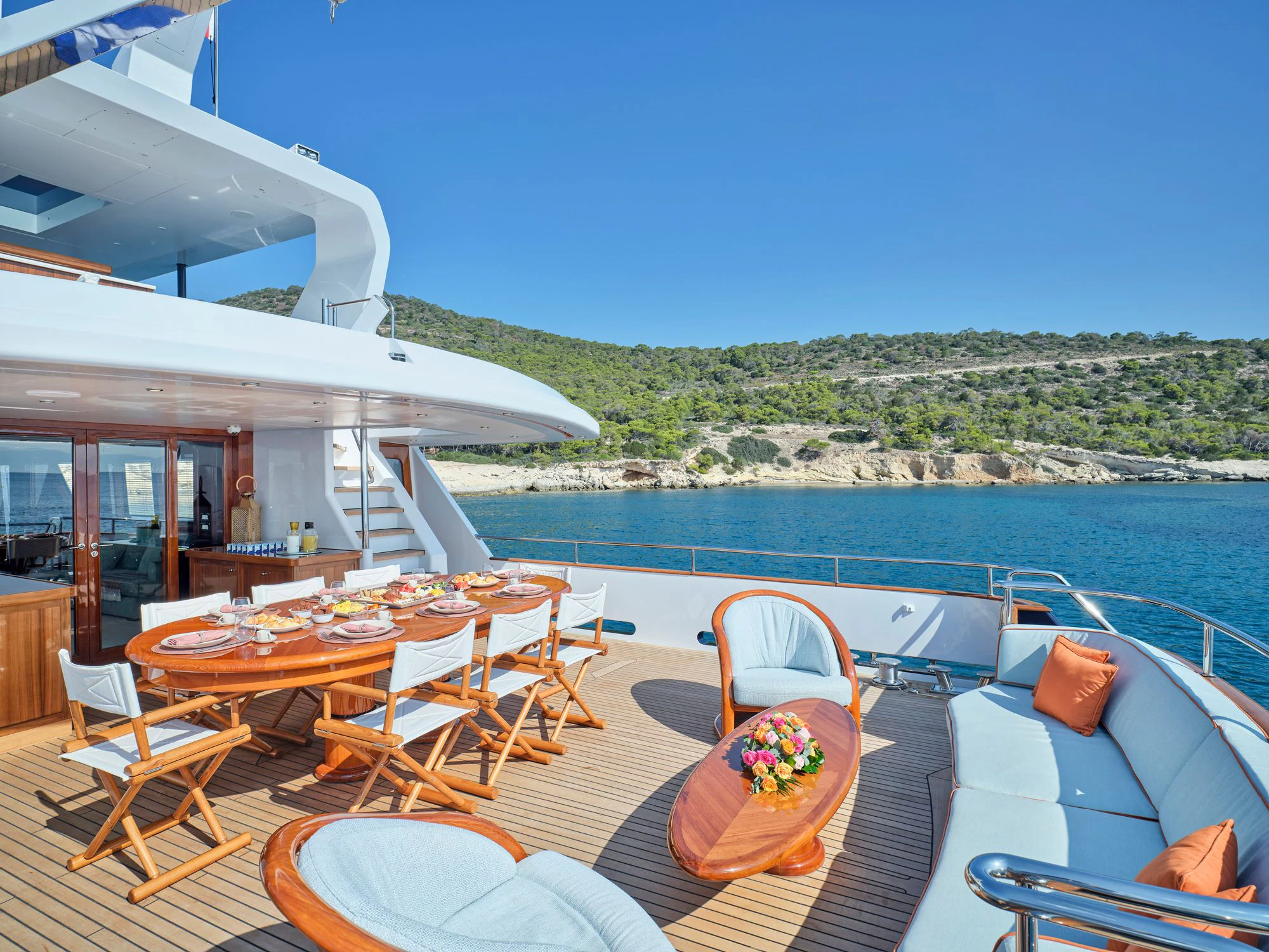 a deck with tables and chairs on it next to a body of water aboard MIA ZOI Yacht for Charter