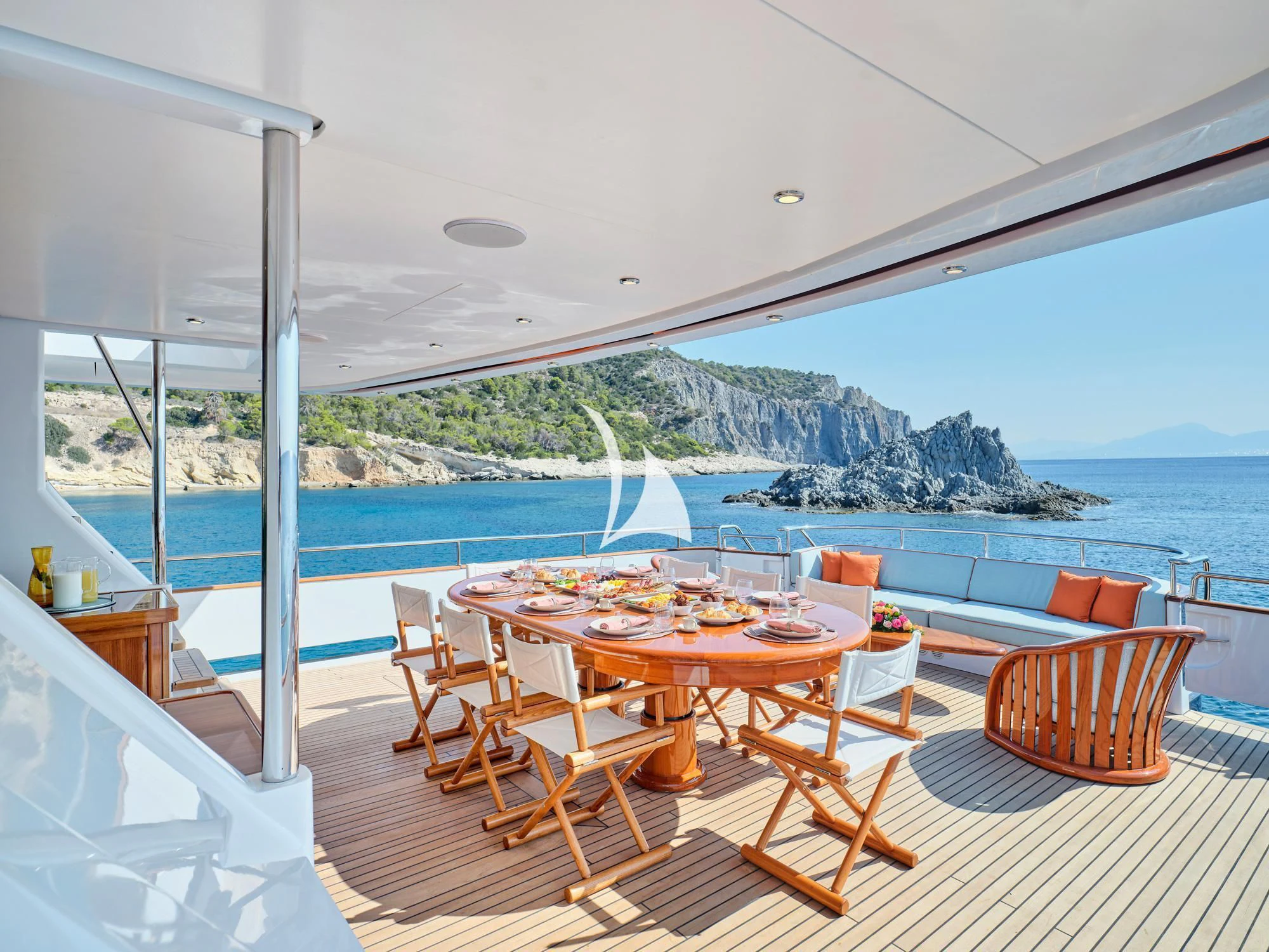 a table and chairs on a deck overlooking a body of water aboard MIA ZOI Yacht for Charter
