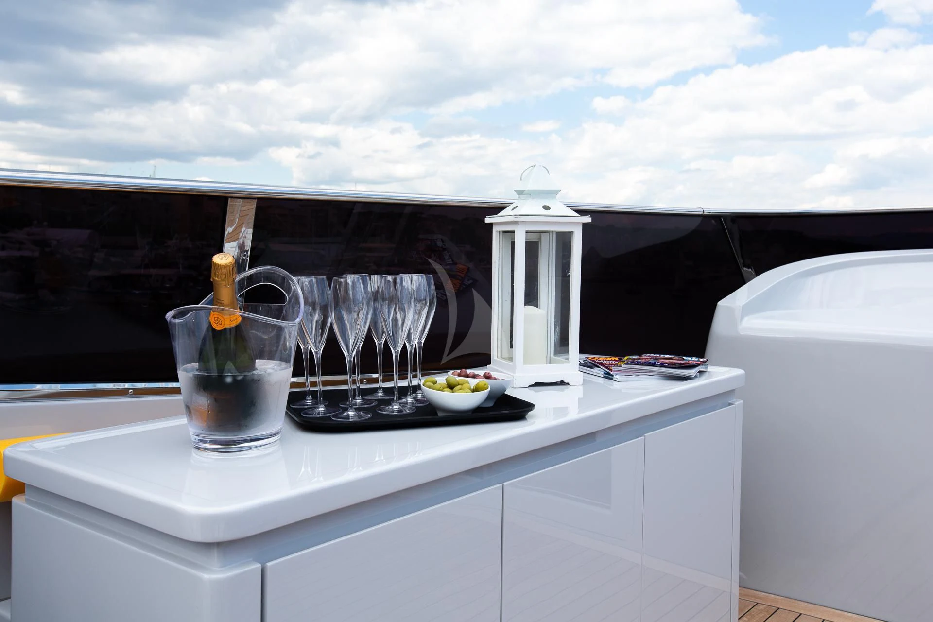 a white counter top with glasses and a bottle of champagne on it aboard CAMILLA A Yacht for Sale