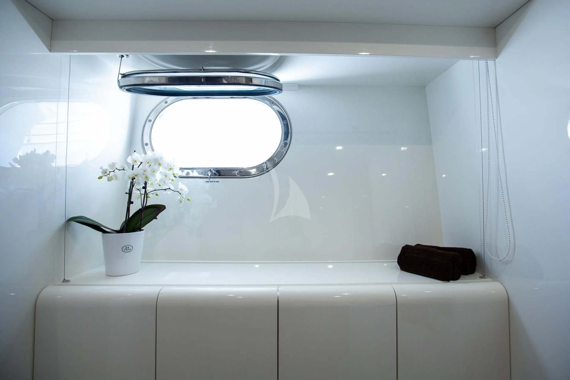 a white bathroom with a plant in a pot on the window sill aboard CAMILLA A Yacht for Sale