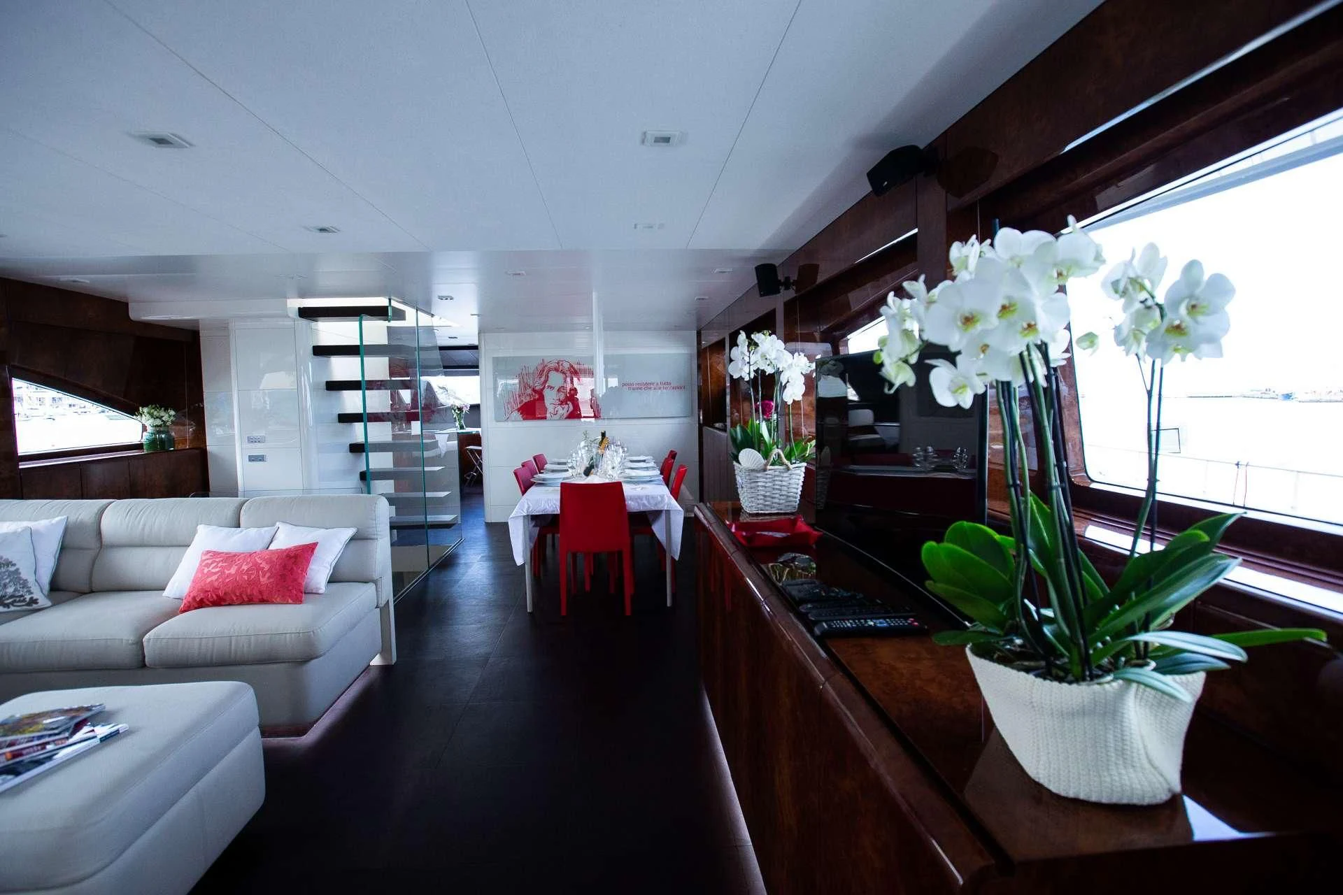 a living room with a white couch and a table with flowers aboard CAMILLA A Yacht for Sale