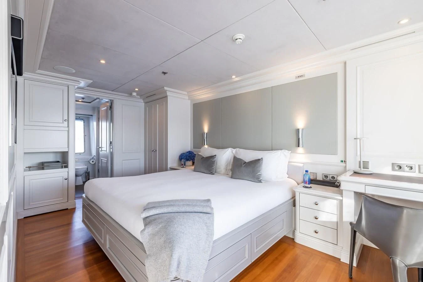 a large white bedroom with a large bed and a desk aboard BRAVADO Yacht for Sale