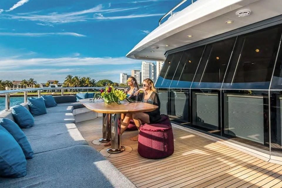 a couple of women sitting at a table outside a large glass window aboard BRAVADO Yacht for Sale