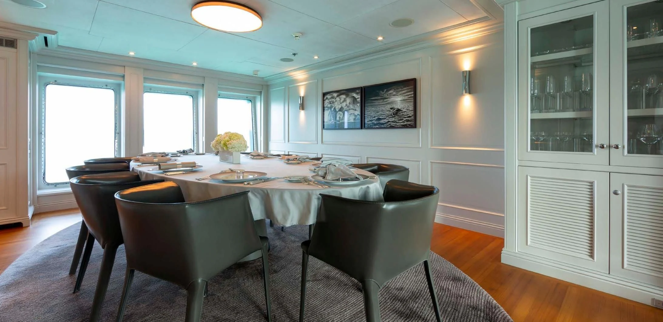 a dining table and chairs in a room with a window aboard BRAVADO Yacht for Sale