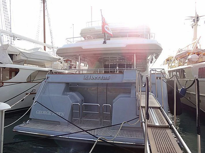 a large white boat with a red flag on the front aboard LIBERTAS Yacht for Sale