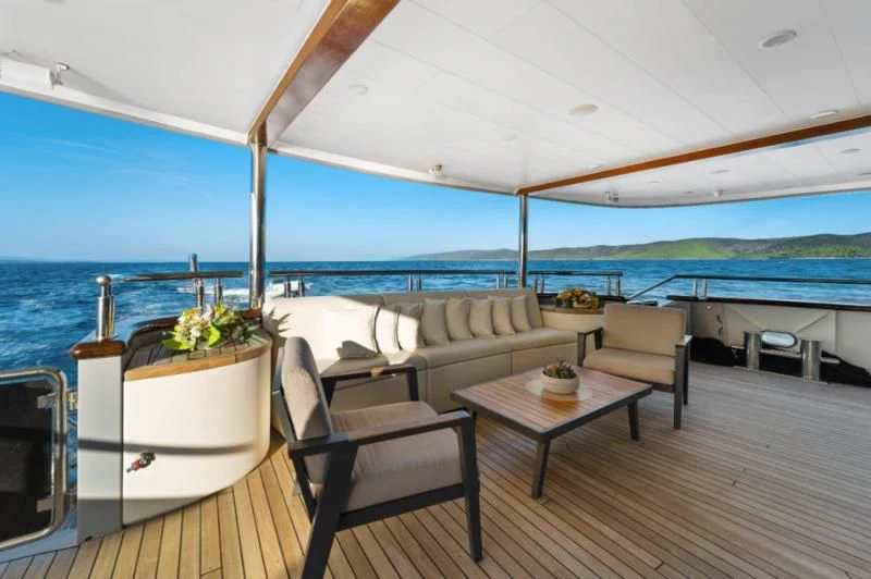 a large white lounge chair next to a table and a large white chair on a deck overlooking the aboard FREEDOM Yacht for Sale