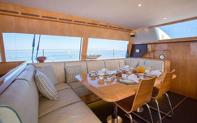 a dining table and chairs in a room with a couch and a window aboard WINDQUEST Yacht for Sale