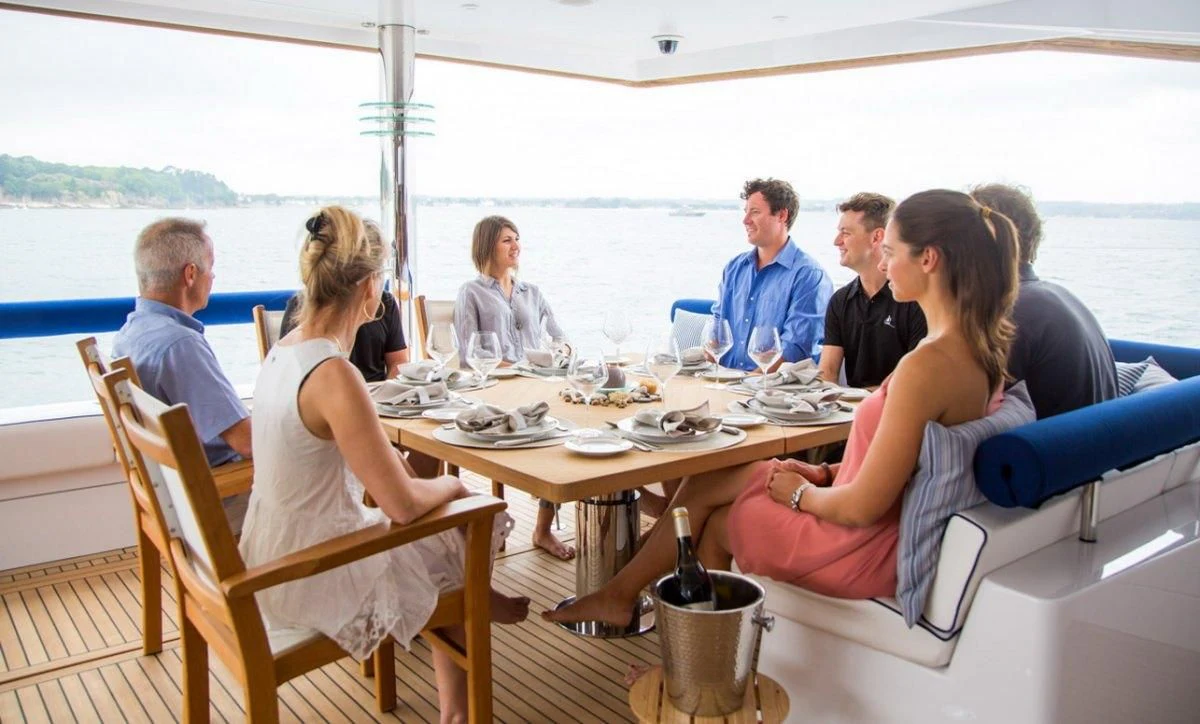 a group of people sitting around a table aboard WINDQUEST Yacht for Sale