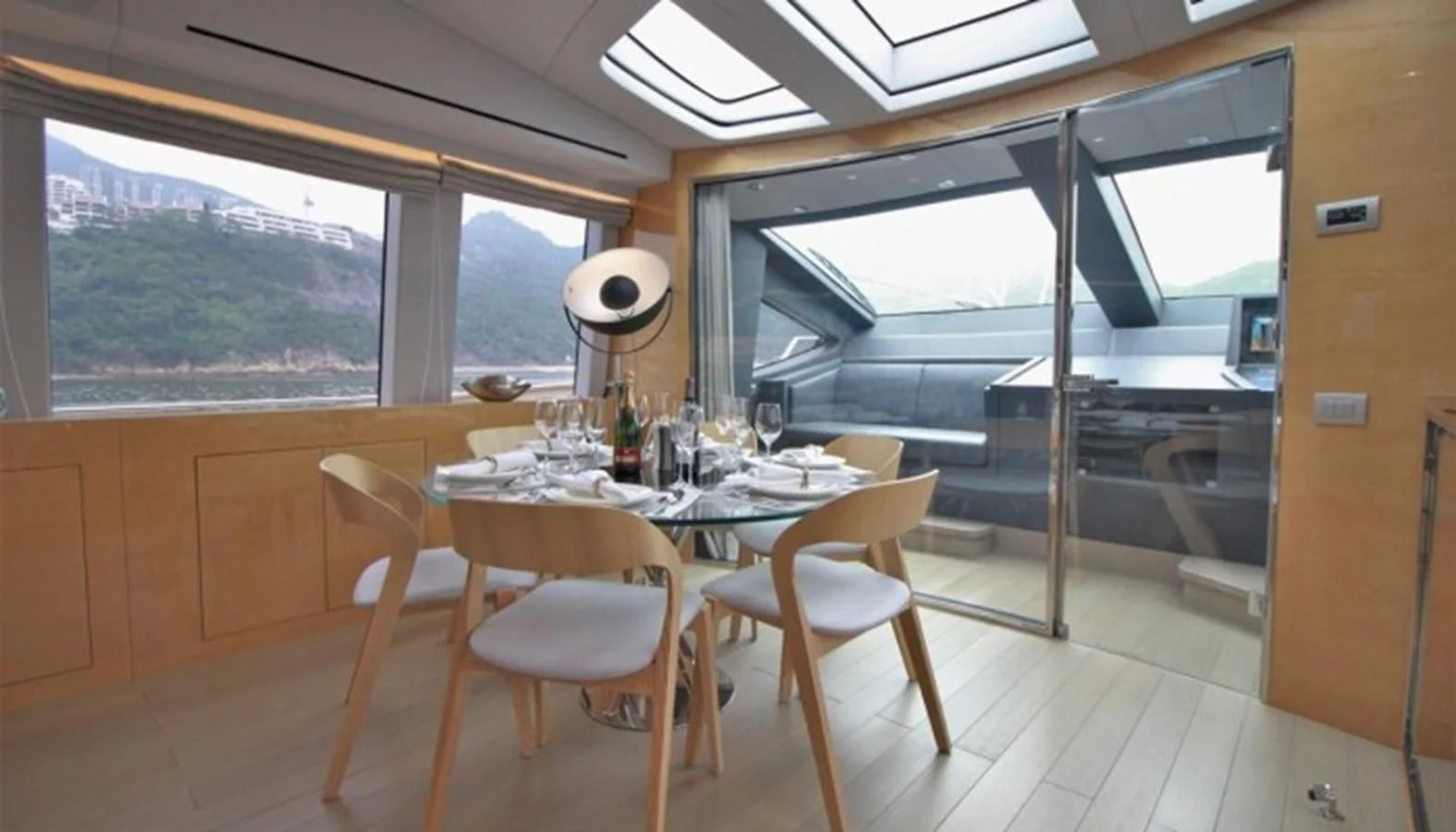 a dining table and chairs in a room with a large window aboard VERSILCRAFT V86 Yacht for Sale