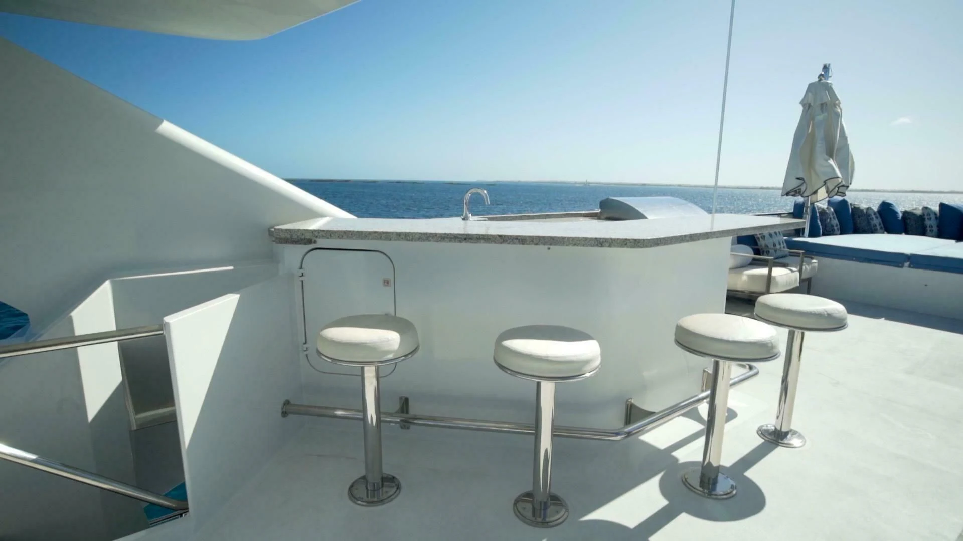 a white table with stools and a chair by a window aboard AT LAST Yacht for Charter