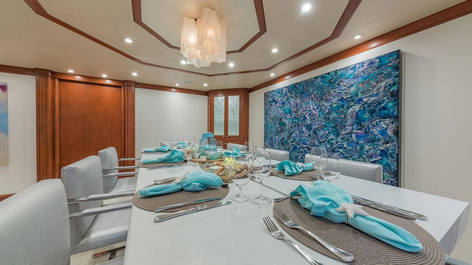 a table with a white tablecloth and a blue wall with white lights aboard AT LAST Yacht for Charter