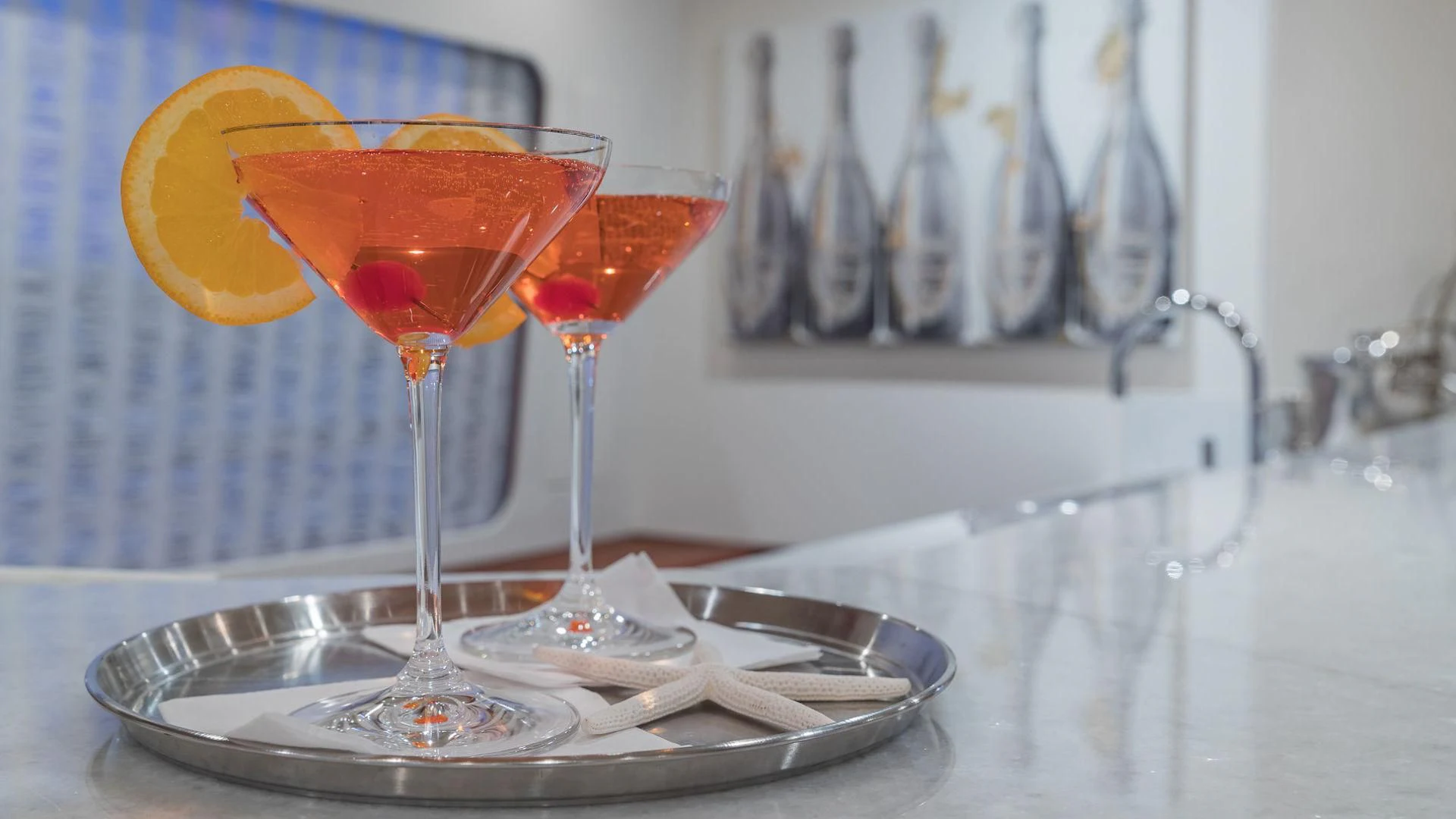 a couple of glasses with red liquid and a lemon wedge on a plate aboard AT LAST Yacht for Charter