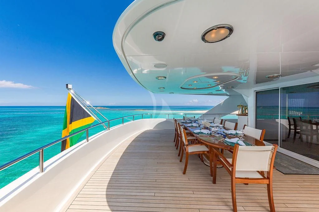 a deck with a table and chairs on it and a view of the ocean aboard AT LAST Yacht for Charter