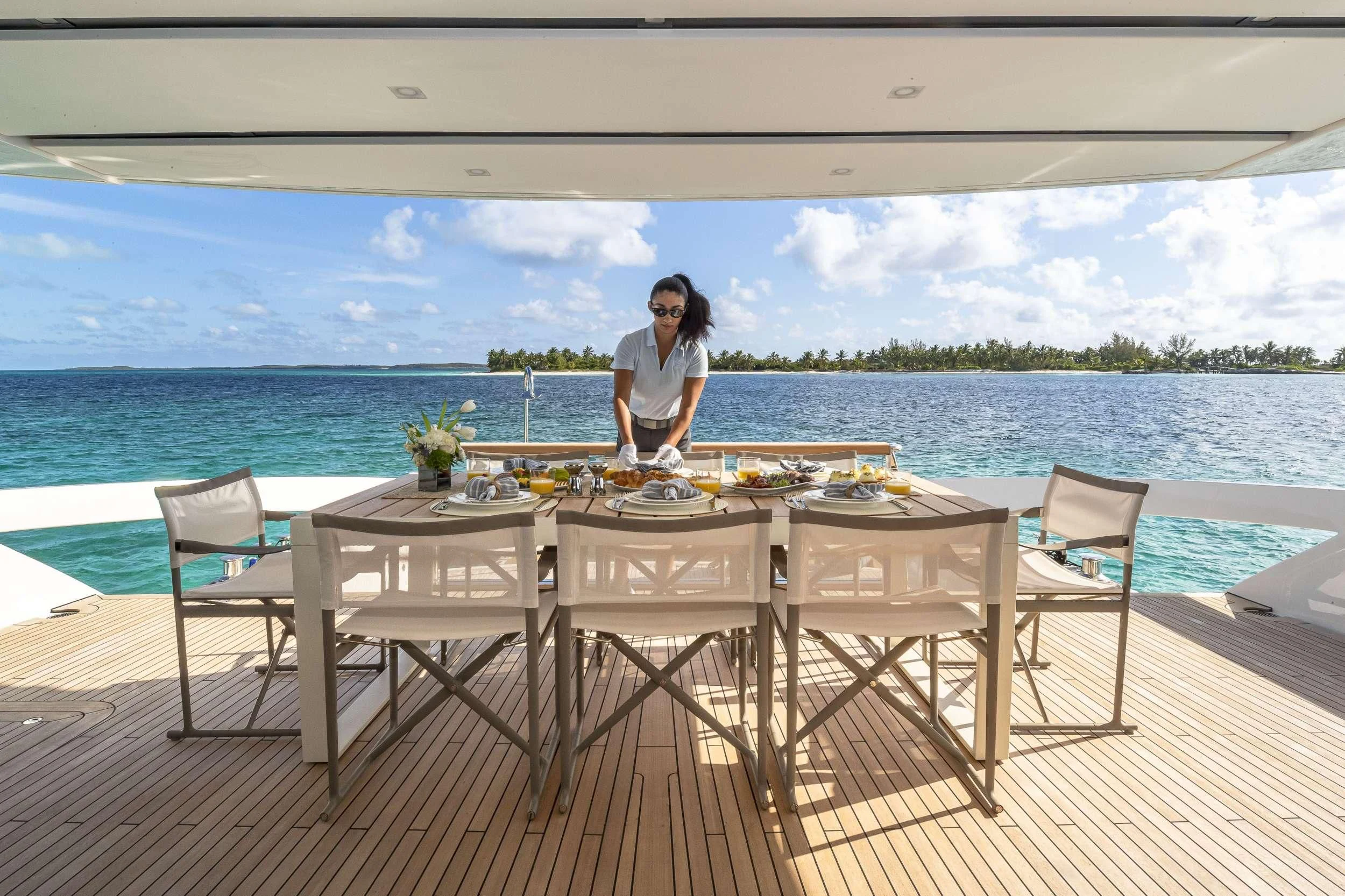 a person sitting at a table on a deck overlooking a body of water aboard NO MATTER WHAT Yacht for Charter