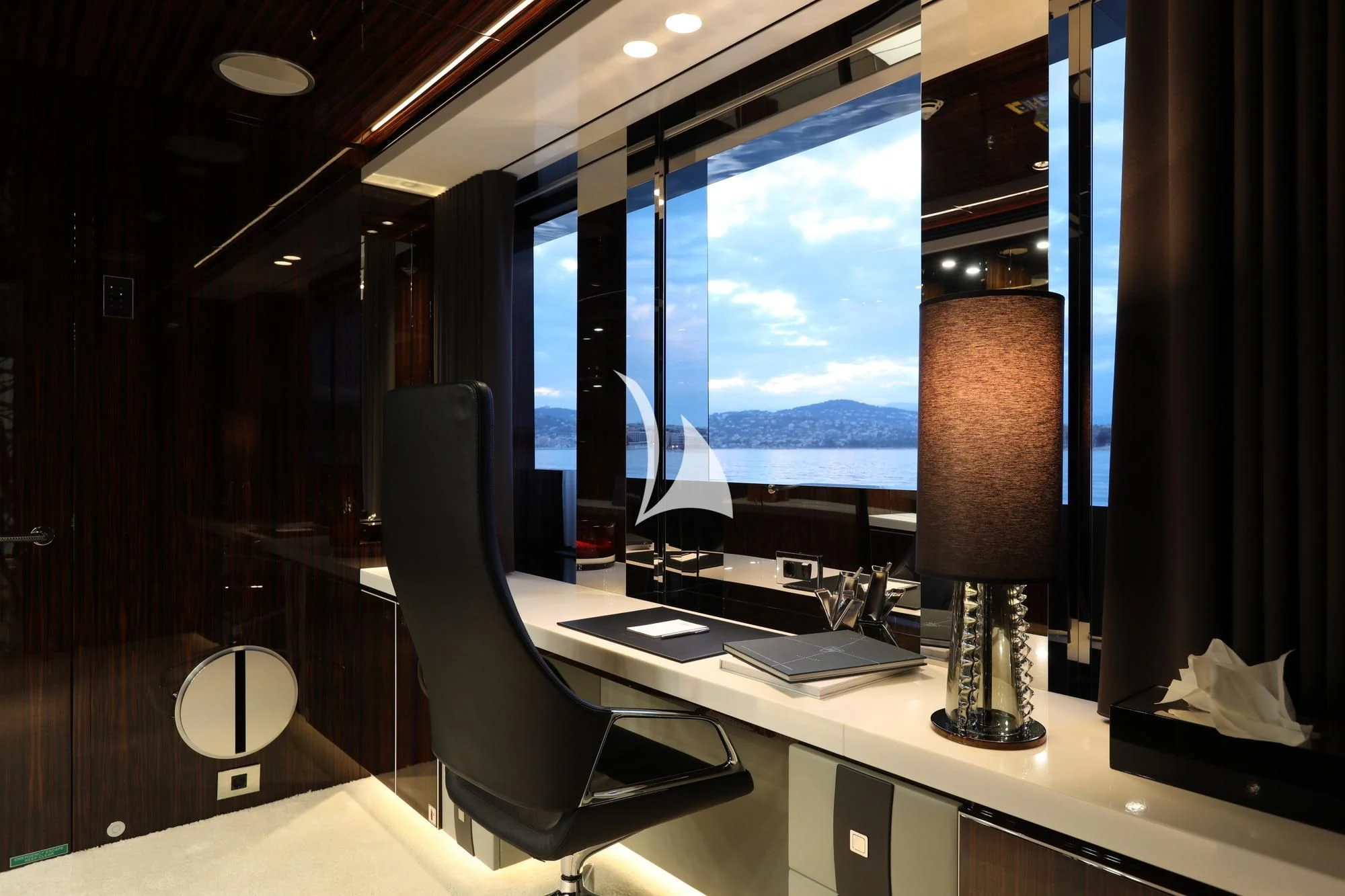 a computer desk with a lamp and a large window aboard PEARL Yacht for Sale