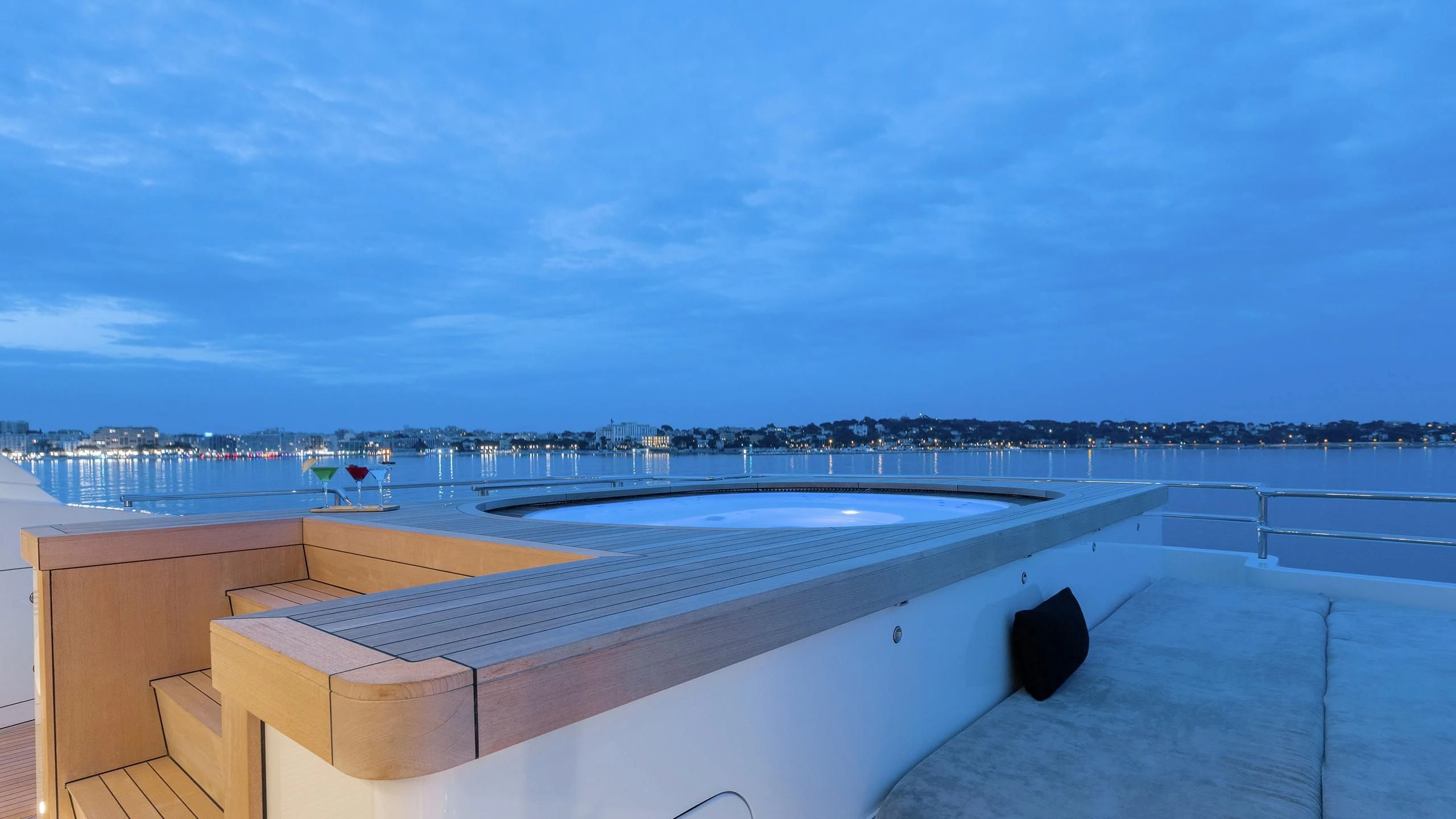 a rooftop with a large building and a body of water in the background aboard PEARL Yacht for Sale