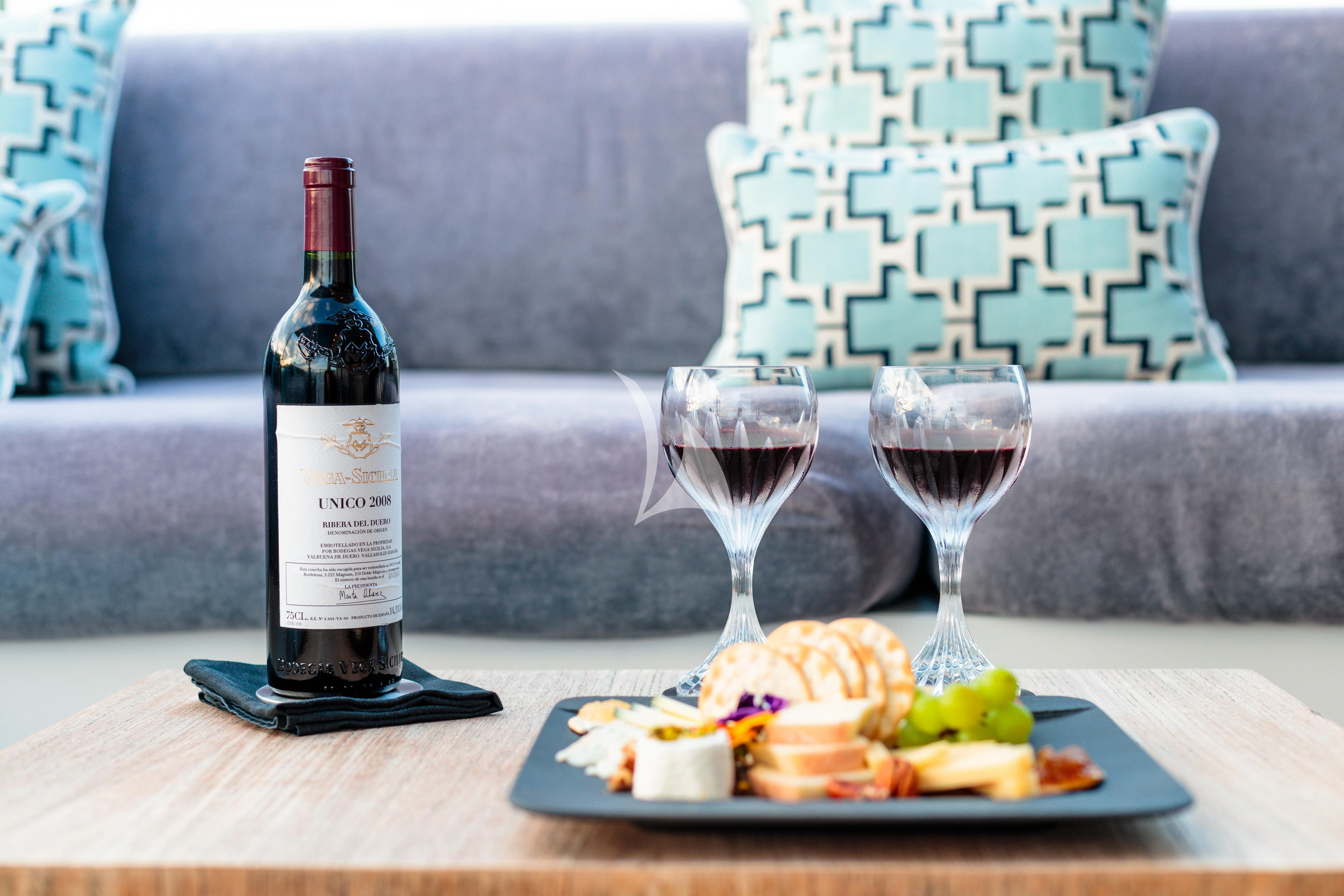 a bottle of wine next to a plate of food and a glass of wine aboard PEARL Yacht for Sale