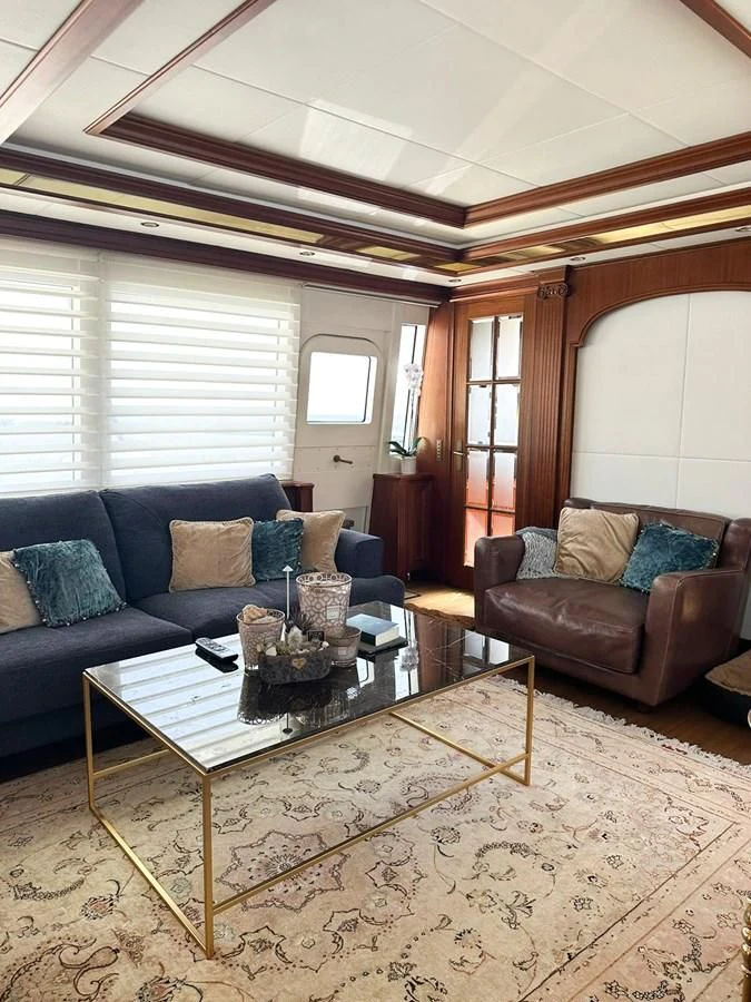 a living room with a blue couch and a coffee table aboard ORION Yacht for Sale