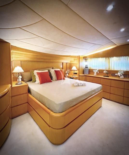 a bed with a white comforter and red pillows aboard LADY A Yacht for Charter