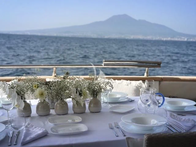 a table set with flowers and a view of the ocean aboard LADY A Yacht for Charter