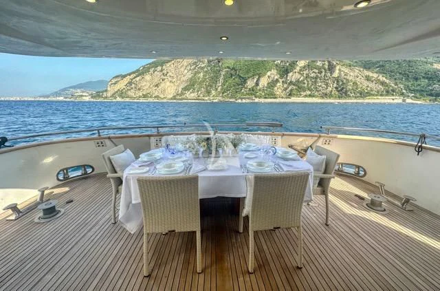 a table set for a meal on a deck overlooking a large body of water aboard LADY A Yacht for Charter