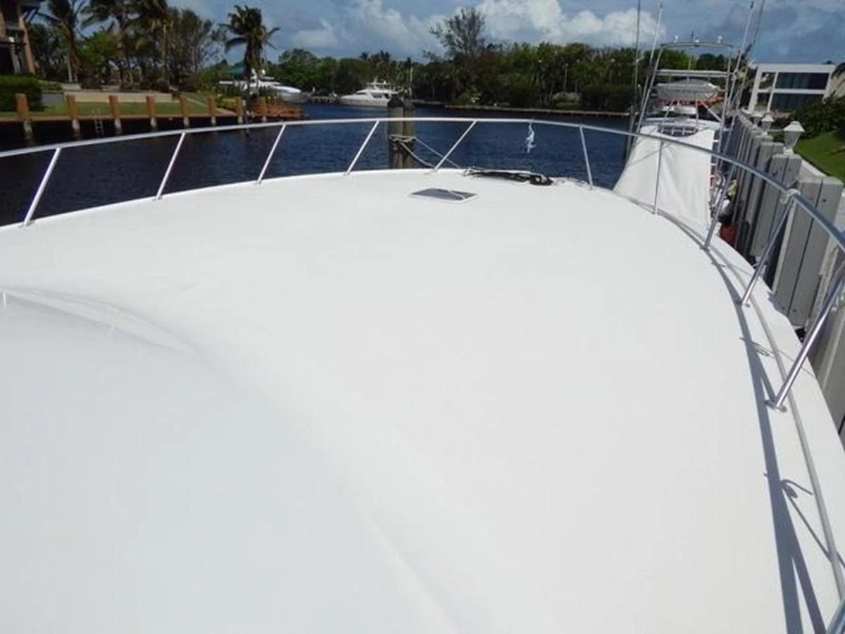 a white surface with a fence and trees in the background aboard ONE MORE TIME Yacht for Sale
